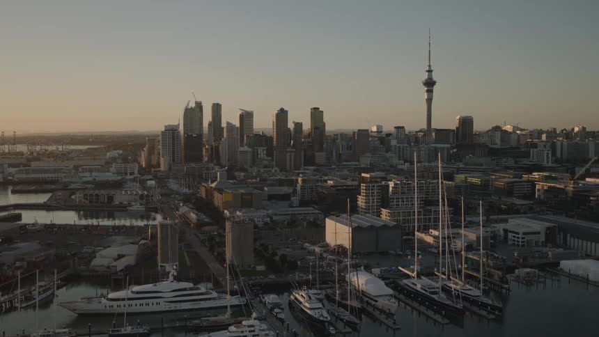 Marina sits across the water from the docks of a large city while red tints the horizon