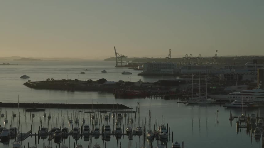 A coastal city with a large port filled with many vessels and huge buildings near the shore