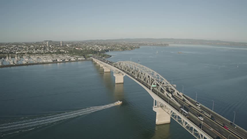 Aerial view of a busy bridge crossing over a large body of water near a coastal city marina