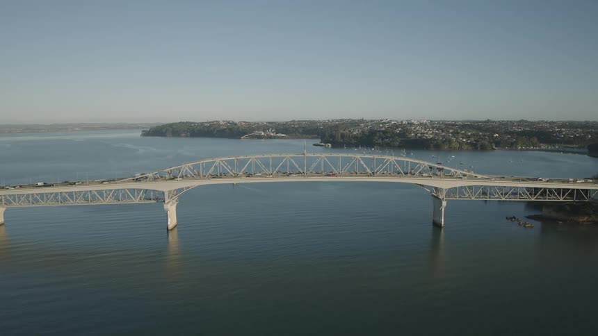 Auckland harbour bridge stretches across the waitemat harbour connecting urbanized shores under a clear sky