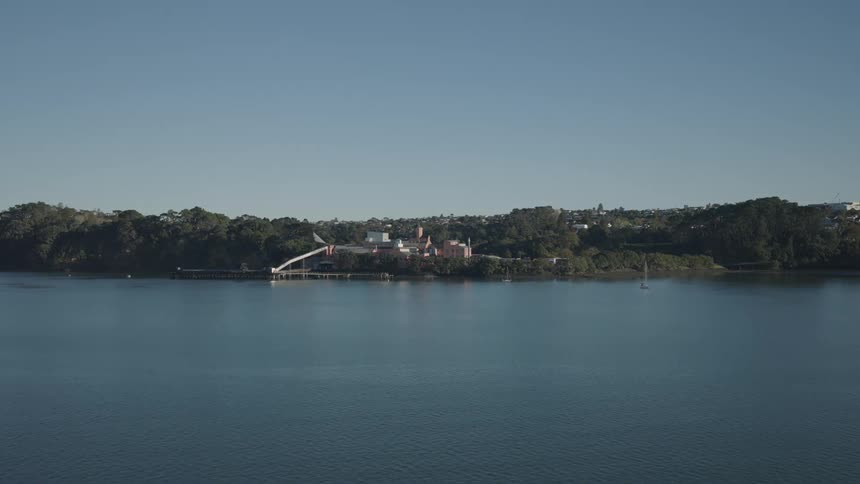 A calm sea and an island with many trees with a port on the coast