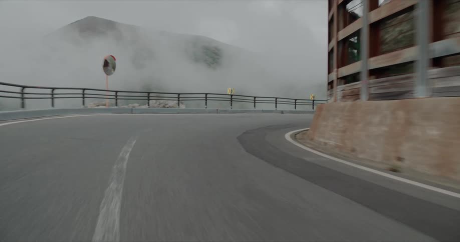 Pointofview shot of a vehicle rapidly driving along a mountain road with a barrier wall on one side