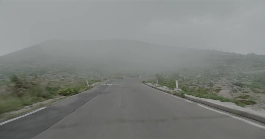 A road winds through the foggy mountains showing clouds settling in the valleys
