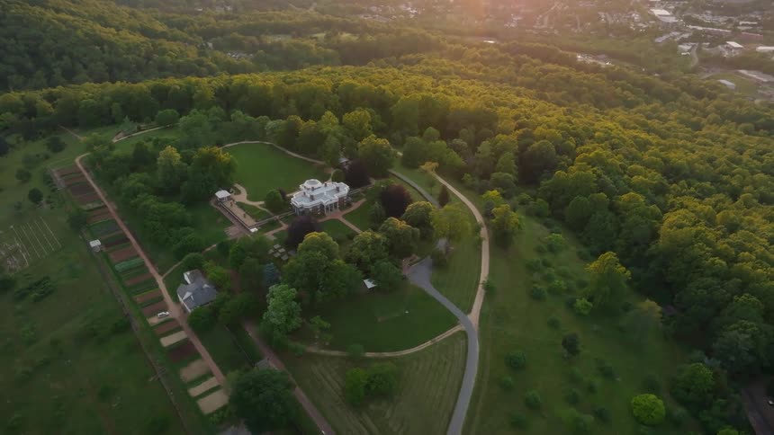 Aerial view of a historical estate surrounded by dense green forest at sunrise