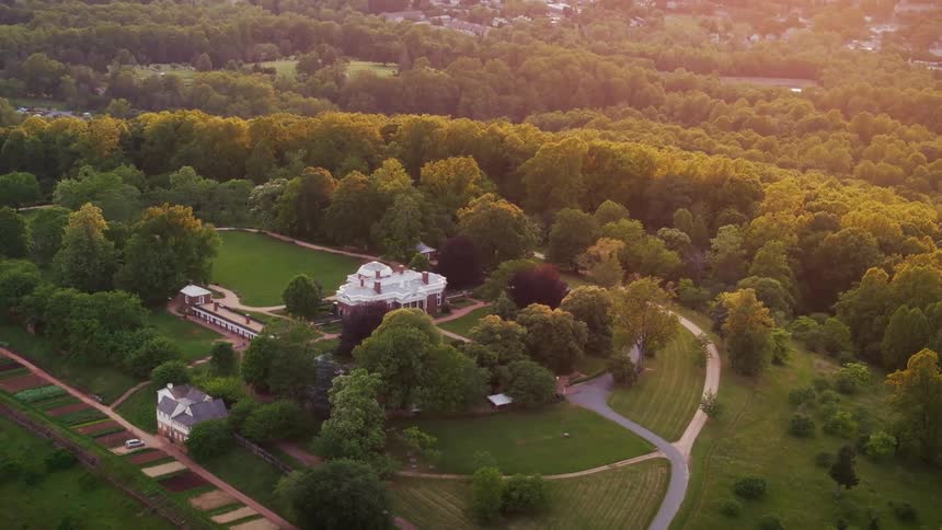 Aerial shot of a historic estate surrounded by dense forest at sunrise