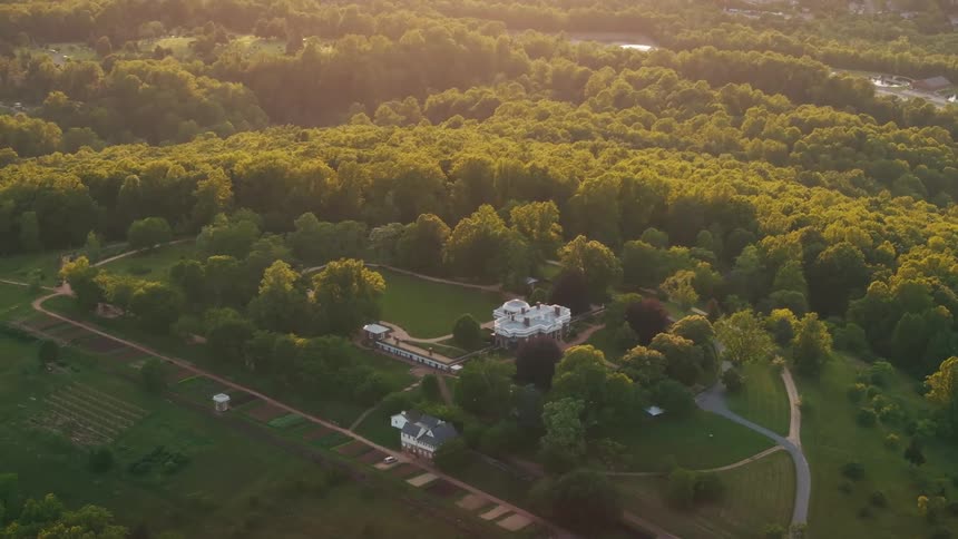 A castle building in the countryside surrounded by lush green vegetation and trees at midday