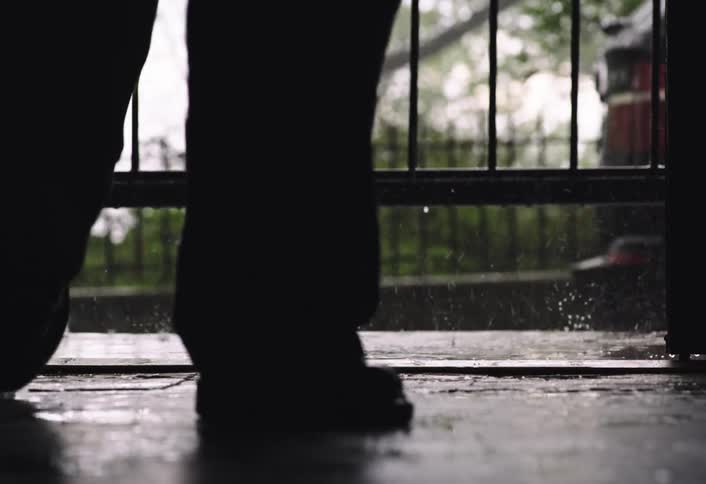 A man walks on the sidewalk as it rains
