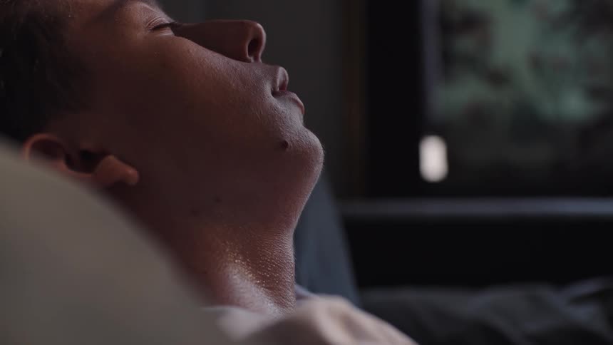 Young man leans against cushions while taking a nap