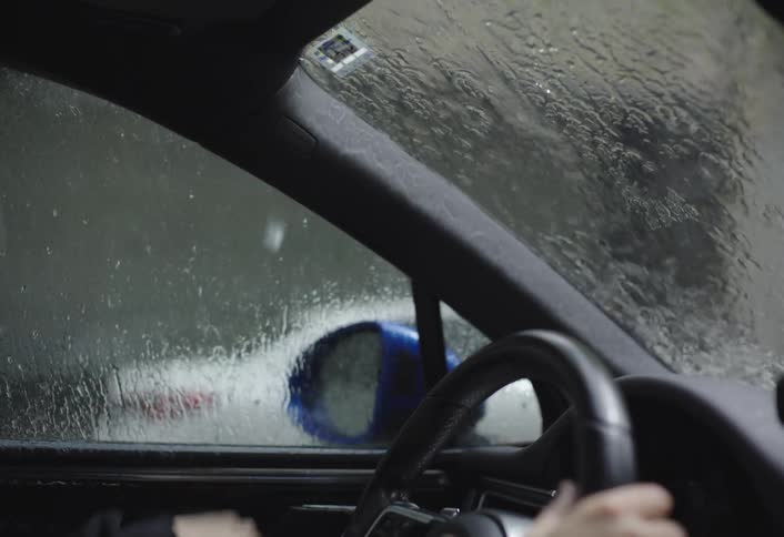 A man running in the rain toward a car