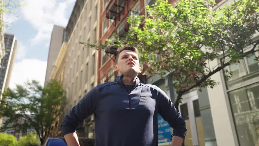 Man straightens and takes a deep breath after working out in a residential area
