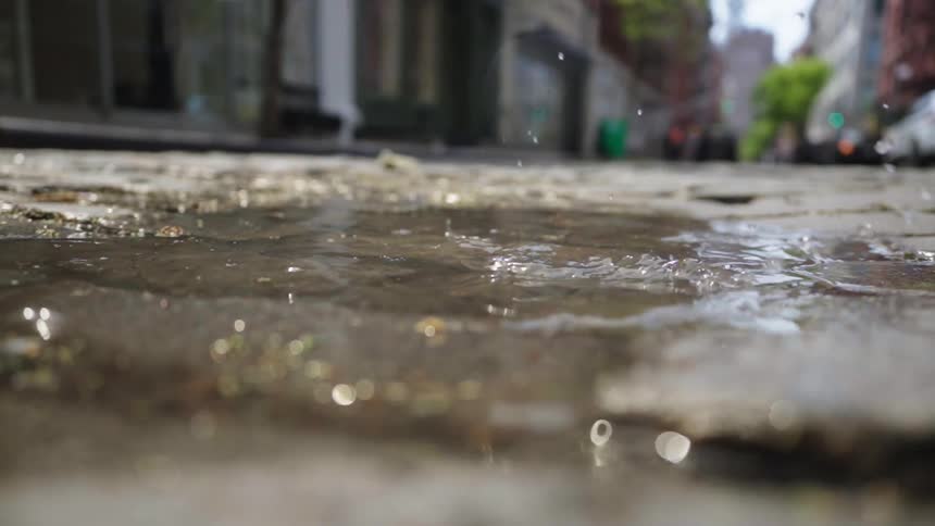 A woman walks and splashes in a puddle with her shoe