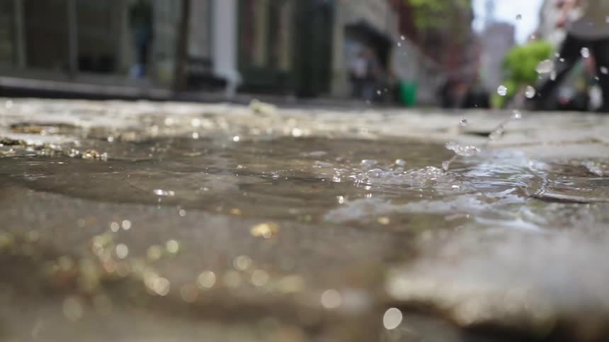 A woman walks on in the puddle on the cobblestone