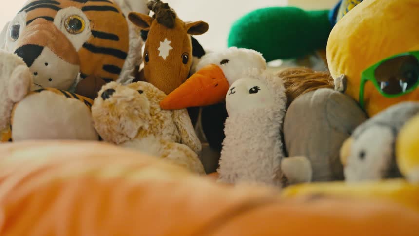 A childs face peers out from a dense pile of various stuffed animals