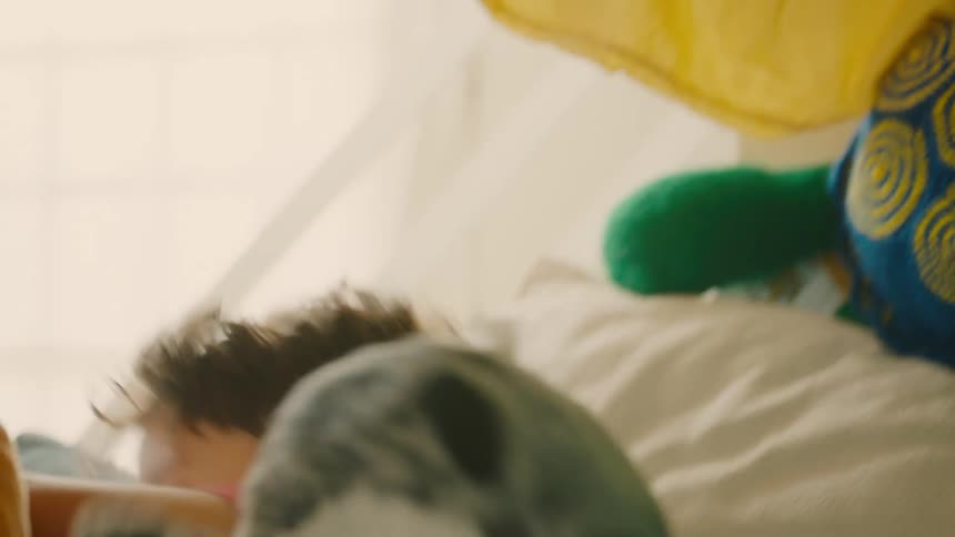 A kid leaps out of a pile of toys