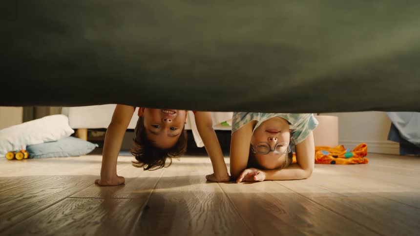 Two children playing upside down in a room