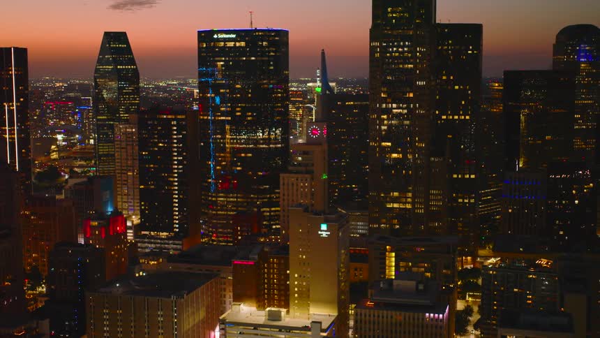 A city skyline filled with highrise buildings and skyscrapers glowing under the warm hues of the sunset