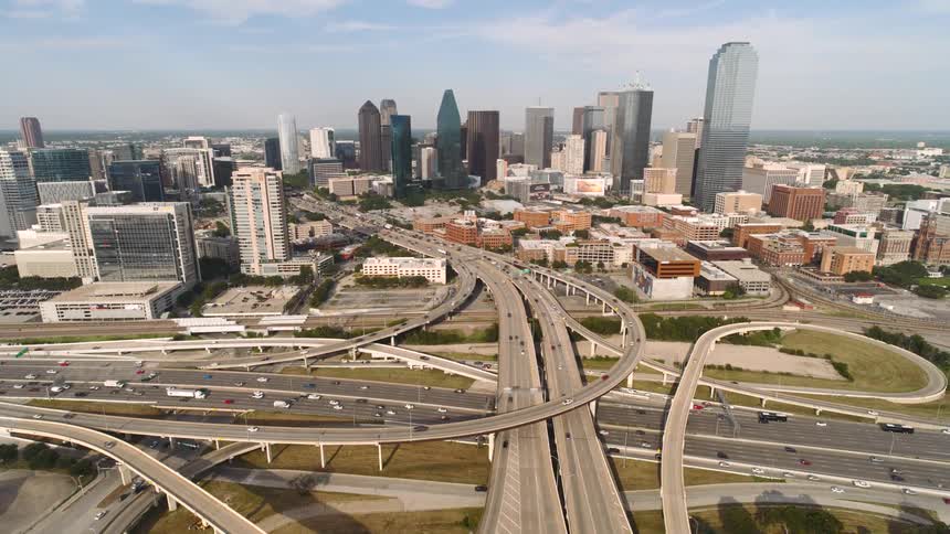 Aerial view of intersections and overpasses with vehicle traffic and a modern metropolis in the background