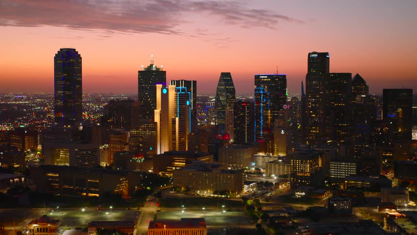 Downtown skyscrapers tower over the surrounding buildings at night under a red sky