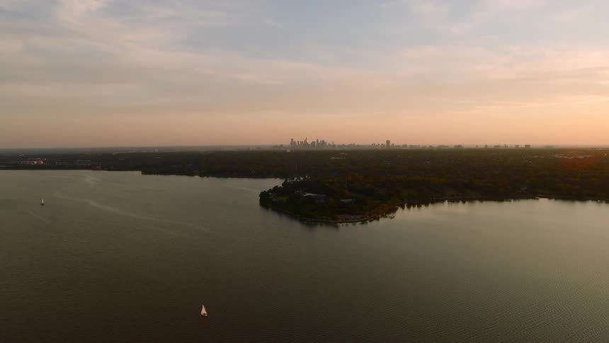 Aerial view of a lake and vegetation in the background with a metropolis on the horizon