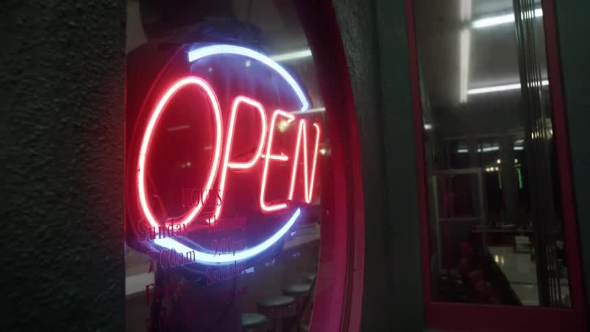 A neon open sign shines in a storefront