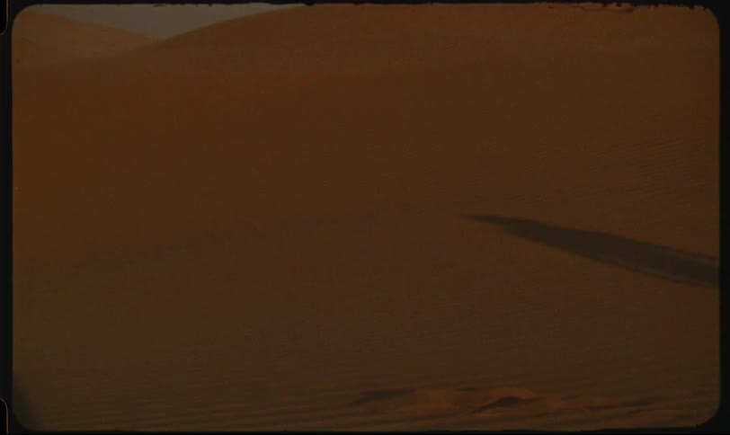 Person casts a shadow while walking in the desert during the daytime