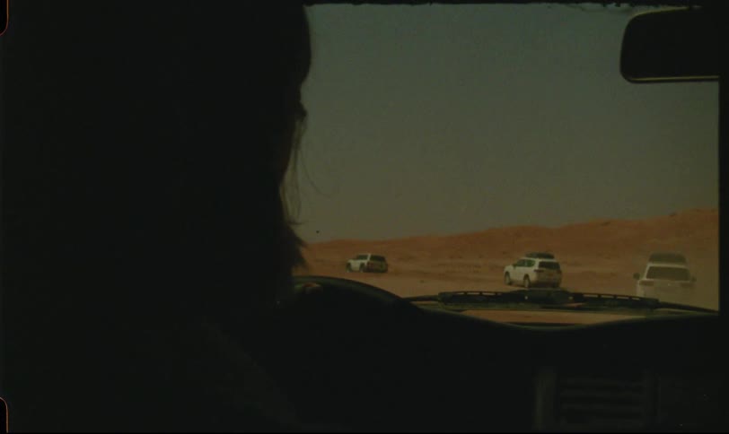 Silhouette of a person driving a vehicle through the desert
