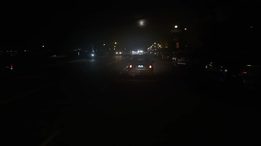 Cars drive down these city streets at night