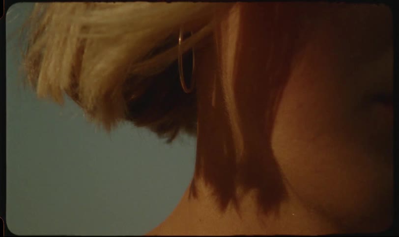 Wind blows the blonde hair of a woman up revealing a hoop earring