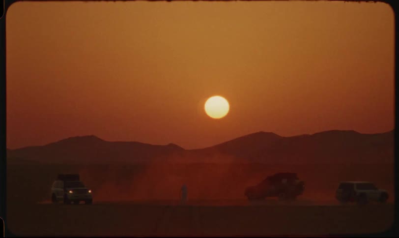 Vehicles in the desert running in a circle and the sunset on the horizon