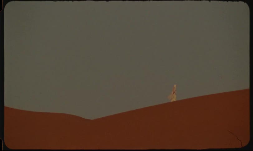 A lone person is walking along a sand dune in a desert landscape