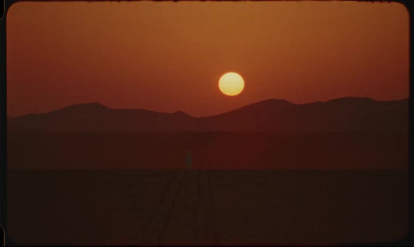 Landscape of a reddish sky with the sunset in the spotlight and silhouettes of desert dunes