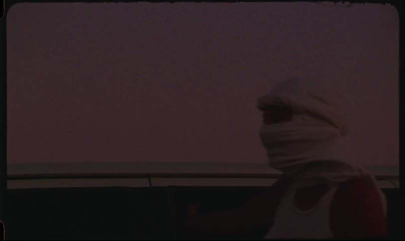 A woman is holding onto a moving car during a desert safari at sunset