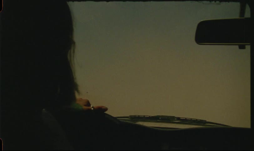 A person rides in a vehicle through a dusty desert following another car barely visible through the haze
