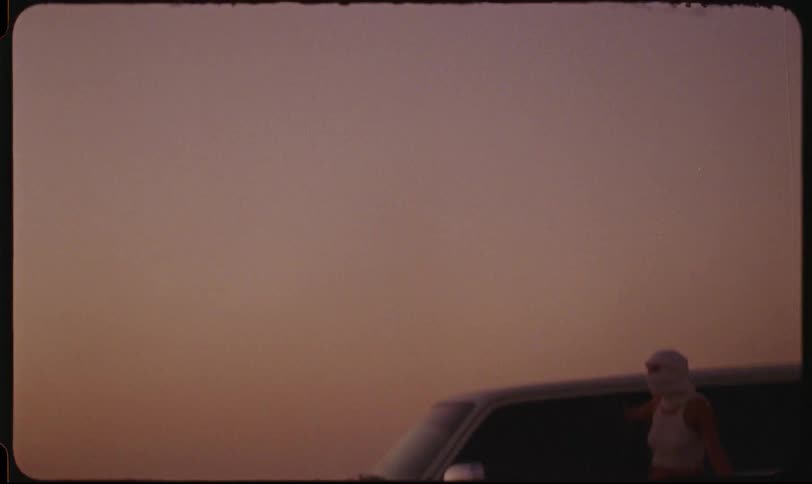 A woman stands beside a white suv during a desert safari at sunset