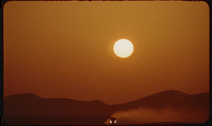 A car in the desert with a sunset