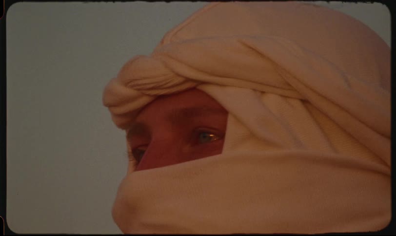 Woman with only her light eyes visible with a white scarf around her face