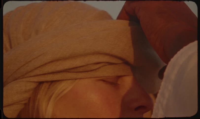 Pair of hands tying a scarf on a blonde womans head