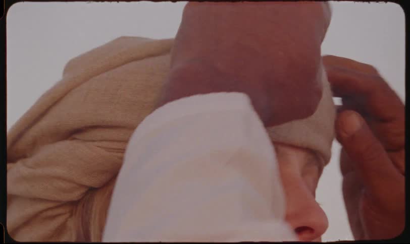 A closeup shot of male hands adjusting a headscarf on a womans head