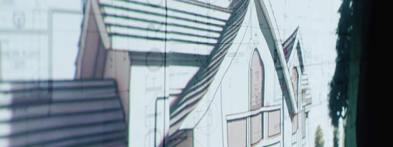 A projection of home drawings is superimposed over blueprints
