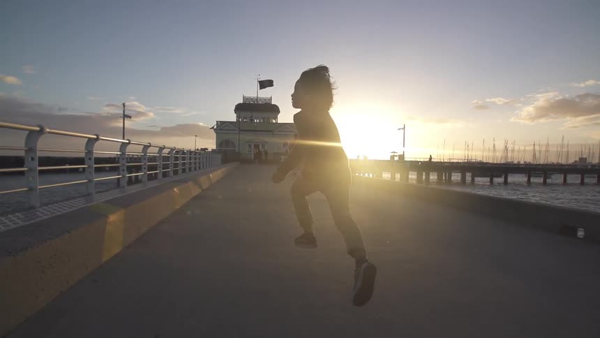 Child running on a bridge over the water