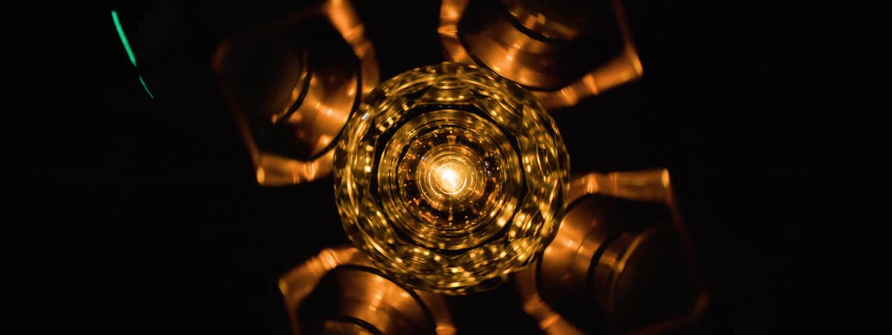 A metal object with protrusions is spinning as lights flash around it