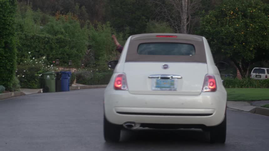 A person waves as they drive off