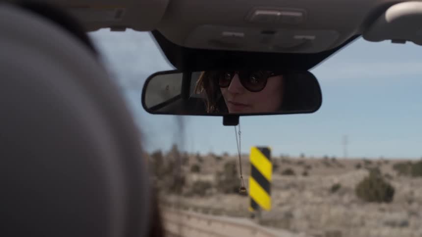 Woman with sunglasses seen in a rearview mirror