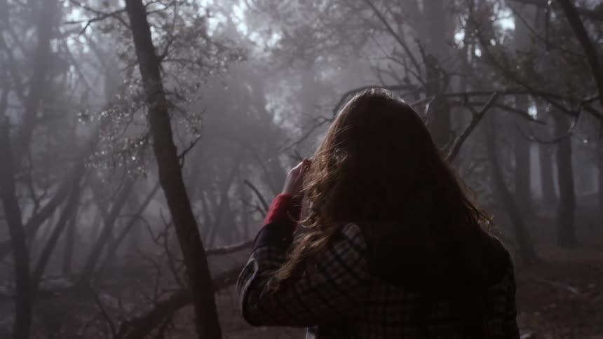 A woman is hiking in a dark forest