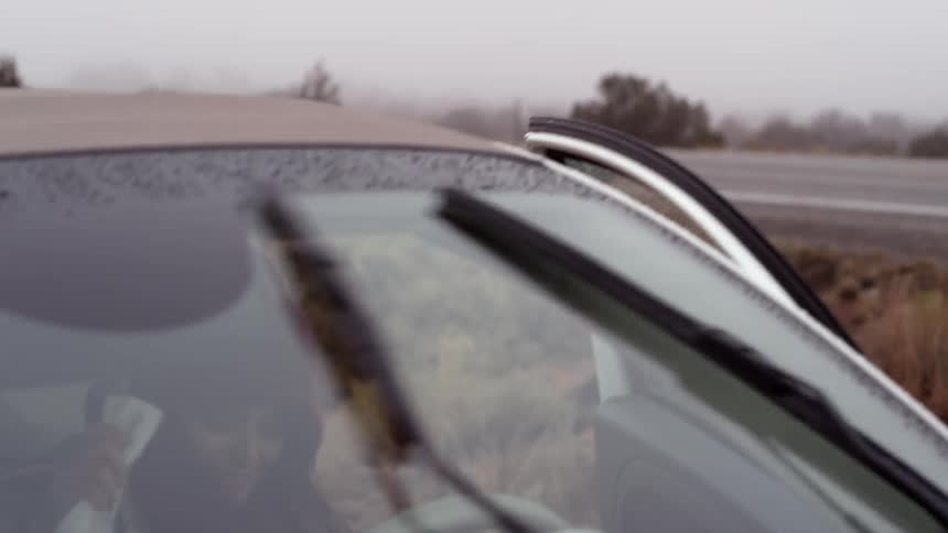 A woman quickly gets in her car on a rainy day