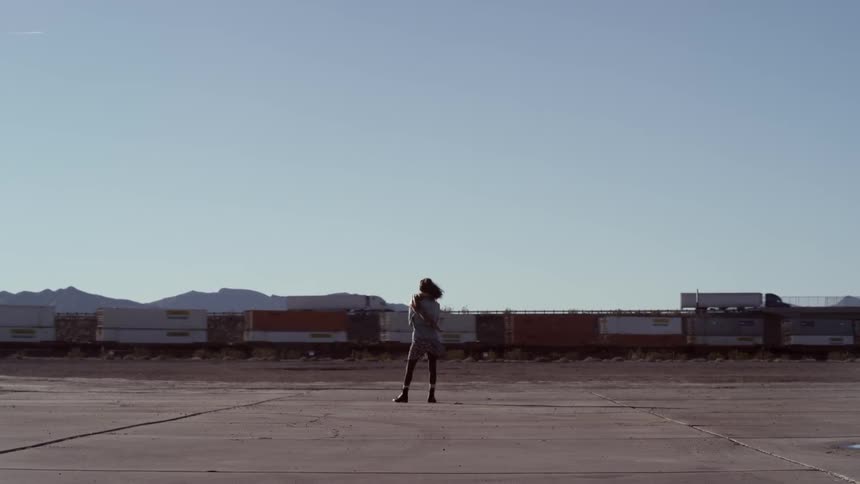 A woman watches a train go by on a clear sunny day