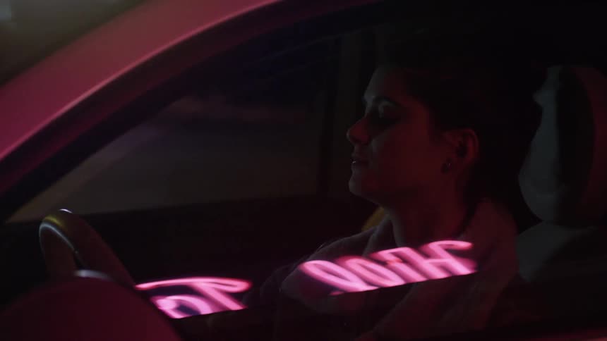 A young woman sitting in a car shifts gears and begins to back up