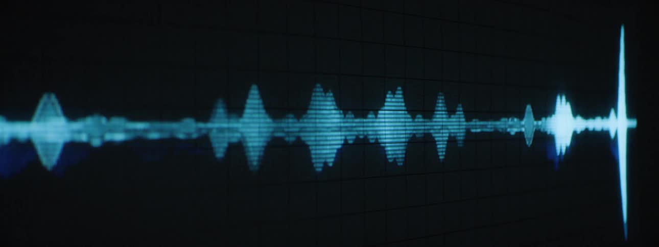 A bright blue waveform undulates horizontally across a dark screen with faint grid lines