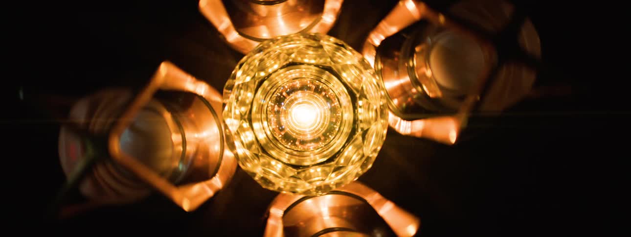 A central multifaceted glowing lamp is surrounded by four illuminated rounded bulbs in a dark setting