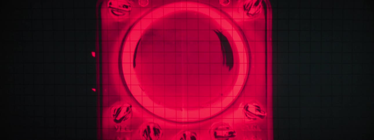 A glowing red graphic on a dark gridded background features a central circular element containing stylized text surrounded by smaller icons and controls